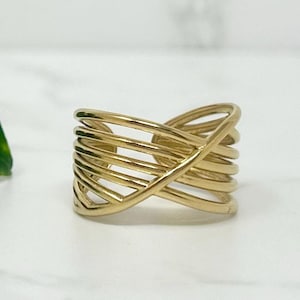 May include: A gold-toned ring with a criss-cross design. The ring is made of multiple thin bands of metal that are woven together.