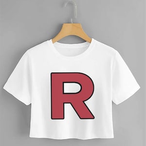 Puede incluir: Camiseta blanca recortada con una gran letra "R" roja impresa en la parte delantera.
