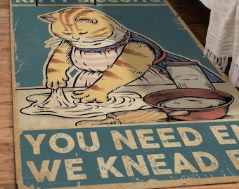May include: A rectangular rug with a vintage design. The rug features a cartoon cat kneading dough, with text that reads "KITTY BISCUITS" and "YOU NEED E WE KNEAD E". The cat is wearing an apron.