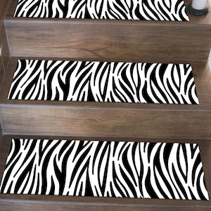 Op de afbeelding: Traptreden met een zebraprintpatroon in zwart en wit. De treden zijn rechthoekig en geplaatst op houten trappen. Het zebrapatroon is een herhalend ontwerp van zwarte strepen op een witte achtergrond.