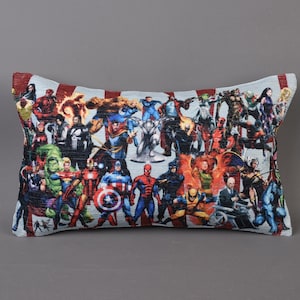 May include: A rectangular pillow with a colorful print of various superheroes. The pillow is made of a soft, textured fabric and features a variety of characters from the Marvel universe.