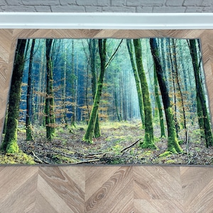 Könnte beinhalten: Ein grüner und blauer Teppich mit einer Waldszene. Der Teppich zeigt einen Weg durch einen moosigen Wald mit hohen Bäumen.
