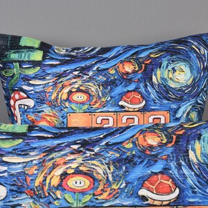 Op de afbeelding: Twee blauwe en witte kussens met een ontwerp ge&iuml;nspireerd op De Sterrennacht met een videogamethema. De kussens bevatten afbeeldingen van paddenstoelen, bloemen en schildpadden.