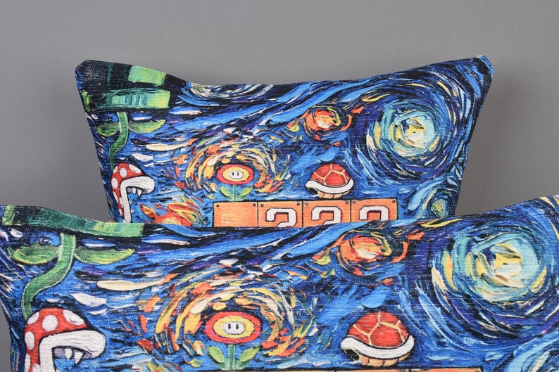 Op de afbeelding: Twee blauwe en witte kussens met een ontwerp ge&iuml;nspireerd op De Sterrennacht met een videogamethema. De kussens bevatten afbeeldingen van paddenstoelen, bloemen en schildpadden.