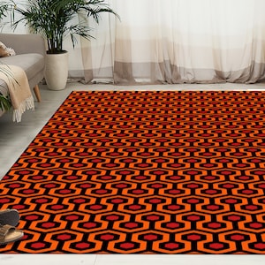 May include: A red and black patterned rug with a geometric design. The rug has a repeating pattern of hexagons and squares.