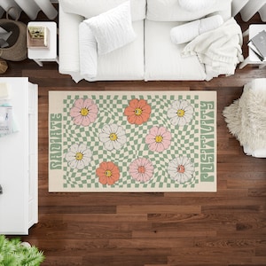 Könnte beinhalten: Ein grün-weiß karierter Teppich mit einem psychedelischen Wirbelmuster. Der Teppich zeigt ein sich wiederholendes Muster aus rosa, weißen und orangefarbenen Blumen mit lächelnden Gesichtern. Der Text "GRAZYPAFES" und "DISRUPTOFFY" ist auf dem Teppich gedruckt.