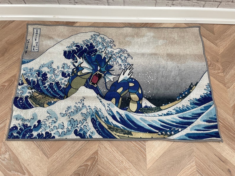 May include: A blue and green Pokemon character, resembling a dragon, emerges from a large wave in a Japanese-style art print. The wave is depicted in shades of blue and white, with a grey background.