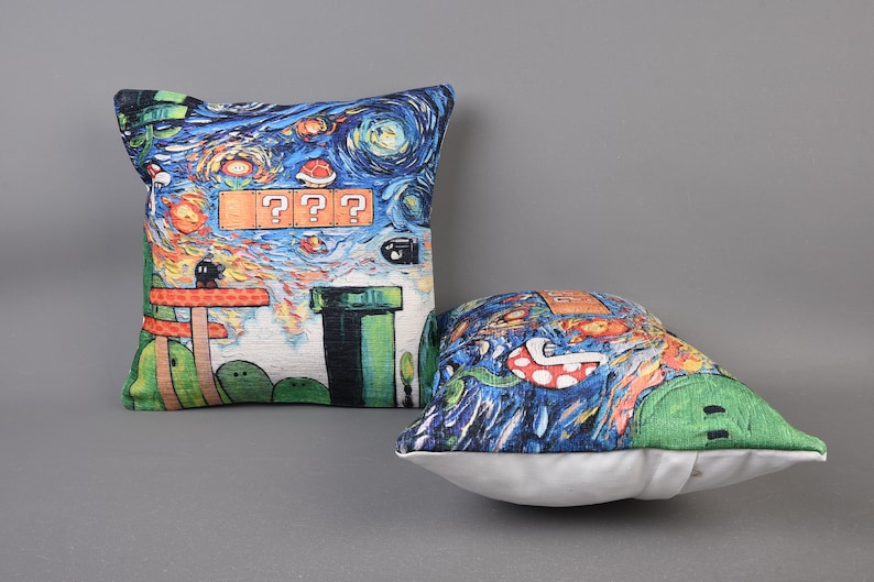 Op de afbeelding: Twee decoratieve kussens met een blauw, groen en oranje pixelontwerp ge&iuml;nspireerd op het videospel Super Mario Bros. De kussens hebben een sterrenhemel als achtergrond en de tekst "???".