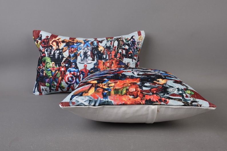 May include: Two decorative throw pillows with a white background and a colorful print of various superheroes. The print features a variety of characters, including Captain America, Iron Man, Thor, and Hulk.