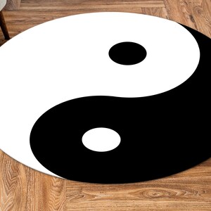May include: A black and white yin yang symbol on a round rug. The rug is on a wooden floor.
