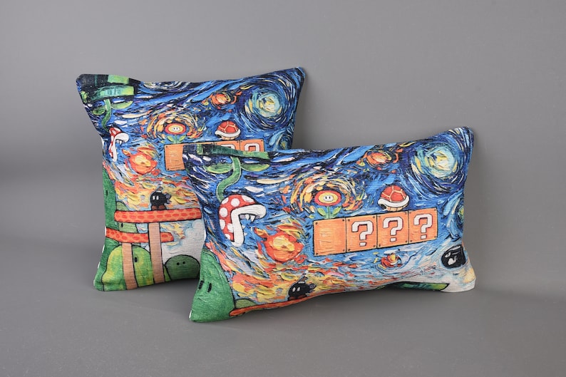 Op de afbeelding: Twee decoratieve kussens met een blauwe, groene, oranje en gele print met een videogamethema. De kussens hebben een Starry Night-achtige achtergrond met vraagtekens en andere videogame-symbolen.