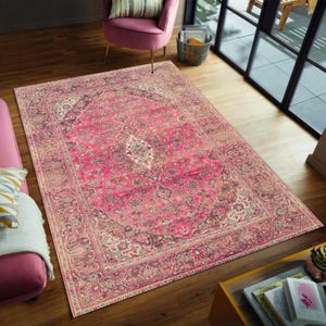 Könnte beinhalten: Ein großer, rechteckiger Teppich mit traditionellem persischem Design. Der Teppich hat ein leuchtend rosa Mittelfeld mit komplizierten floralen und geometrischen Mustern in Rosa-, Grau- und Cremetönen. Der Rand ist in einem dunkleren Rosaton gehalten.