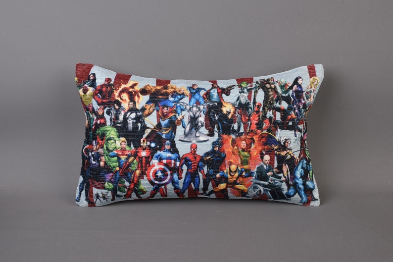 May include: A rectangular pillow with a colorful print of various superheroes. The pillow is made of a soft, textured fabric and features a variety of characters from the Marvel universe.