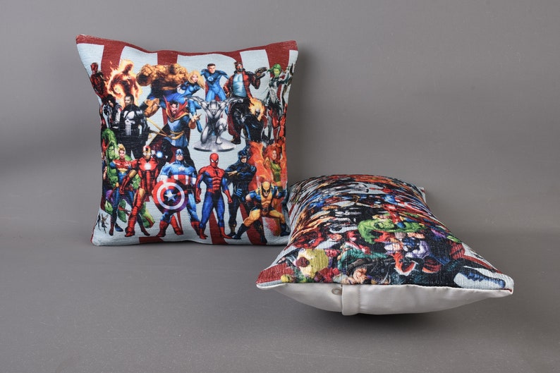 May include: Two decorative throw pillows with a superhero theme. The pillows are made of a soft, plush fabric and feature a colorful print of various superheroes.