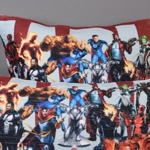 May include: Two decorative throw pillows with a colorful print of various superheroes. The pillows are made of a soft, textured fabric and feature a variety of characters from the Marvel universe.