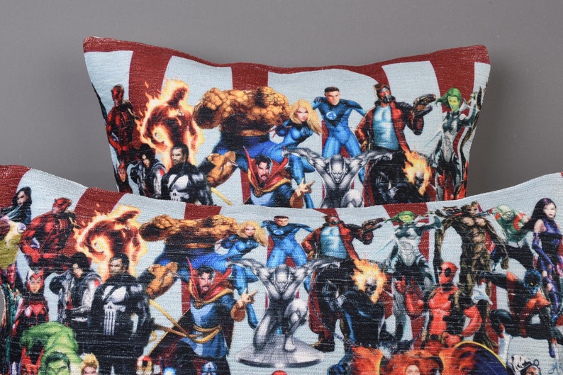 May include: Two decorative throw pillows with a colorful print of various superheroes. The pillows are made of a soft, textured fabric and feature a variety of characters from the Marvel universe.