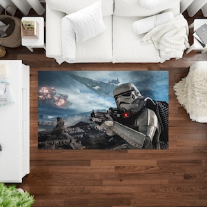 Könnte beinhalten: Ein Star Wars-Teppich mit einem Stormtrooper, der mit einem Blastergewehr zielt. Im Hintergrund ist ein Raumschiff zu sehen, das über eine felsige Landschaft fliegt.