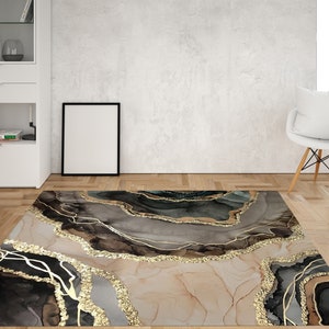 Può includere: Tappeto da area astratto con un designo grigio, nero e oro. Il tappeto presenta un motivo a spirale di linee e forme dorate su uno sfondo grigio e nero.