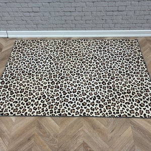 May include: A white and brown leopard print area rug with a gray border.