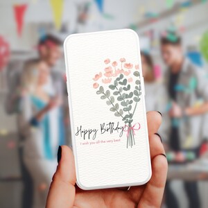 May include: A white smartphone with a pink and green floral design and the text "Happy Birthday! I wish you all the very best." on the screen.