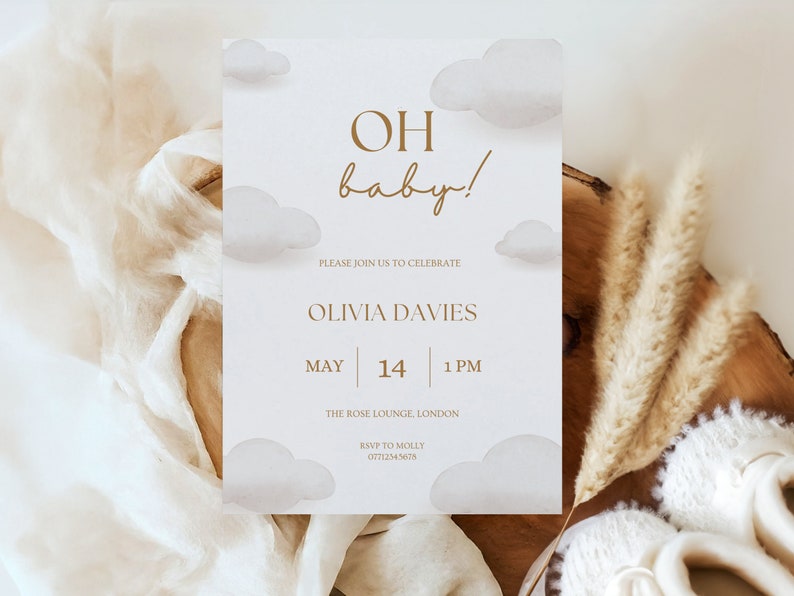 May include: A baby shower invitation with a white background and gold text. The invitation features a watercolor illustration of clouds and the text "OH baby!"  The invitation also includes the date, time, and location of the shower. RSVP information is included at the bottom.