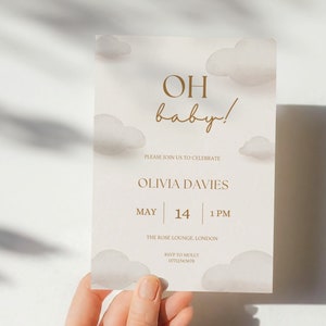 May include: A baby shower invitation with a cloud design and the text "OH baby!" in gold lettering. The invitation includes the name Olivia Davies, the date May 14, the time 1 PM, the location The Rose Lounge, London, and the RSVP information.