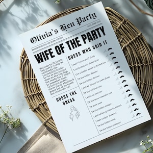 May include: A black and white printed game sheet for a bachelorette party, titled "Wife of the Party." The sheet includes a "Guess Who Said It" game with various statements and a "Guess the Dress" section. The sheet is on a woven basket.