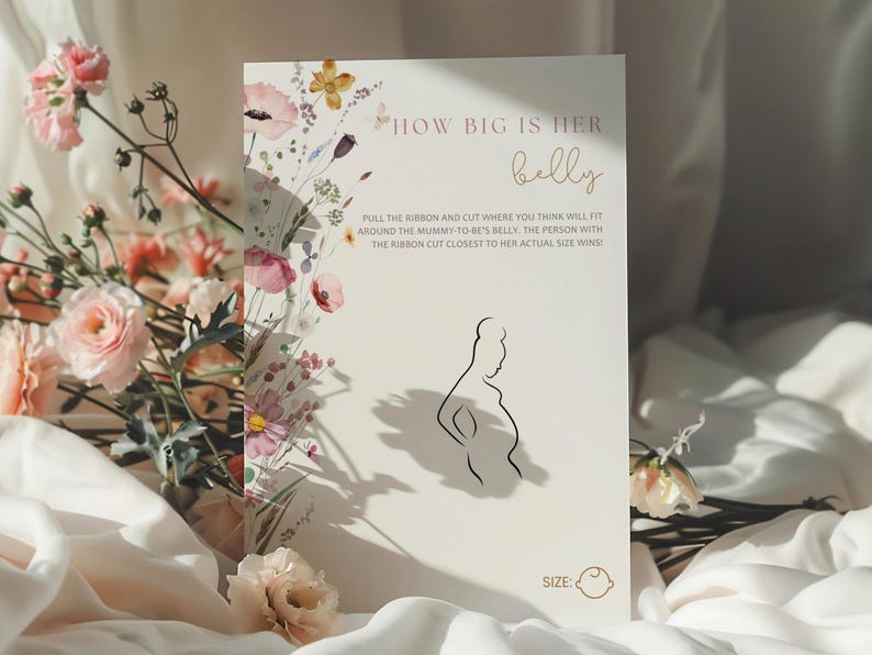 Op de afbeelding: Een witte kaart met een bloemenontwerp en de tekst "HOW BIG IS HER belly" in roze en gouden letters. De kaart bevat ook instructies voor een spel: "PULL THE RIBBON AND CUT WHERE YOU THINK WILL FIT AROUND THE MUMMY-TO-BE'S BELLY. THE PERSON WITH THE RIBBON CUT CLOSEST TO HER ACTUAL SIZE WINS!" en een silhouet van een zwangere vrouw.