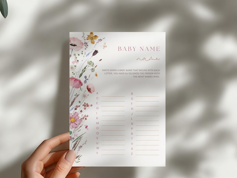 Op de afbeelding: Een printbare babyshower-spelkaart met een bloemenontwerp. De kaart heeft de titel "Baby Name" en instructies om een babynaam op te schrijven die begint met elke letter van het alfabet. De persoon met de meeste namen wint.