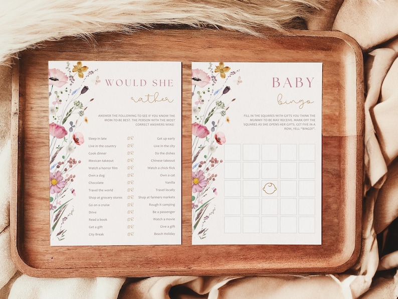 Op de afbeelding: Twee afdrukbare babyborrelspelkaarten met een bloemenontwerp. De eerste kaart is een "Would She Rather"-spel met een lijst met vragen. De tweede kaart is een "Baby Bingo"-spel met een raster van vierkanten om in te vullen.