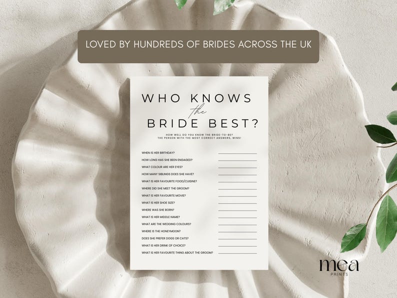 May include: A white card with the text "WHO KNOWS THE BRIDE BEST?" in a minimalist font. The card includes fill-in-the-blank questions about the bride. The card is on a textured, off-white surface. The text "LOVED BY HUNDREDS OF BRIDES ACROSS THE UK" is at the top.
