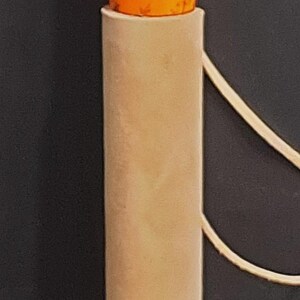 May include: A cylindrical walking stick featuring a dark brown wooden upper section, a bright orange middle section with etched floral patterns, and a smooth beige leather grip. A small white cord is tied in a knot near the top of the orange section.