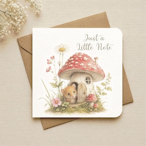May include: A square greeting card with a brown envelope featuring a watercolour illustration of a small brown mouse peeking out from a red and white mushroom house. The text Just a Little Note is printed in grey script above the mushroom.