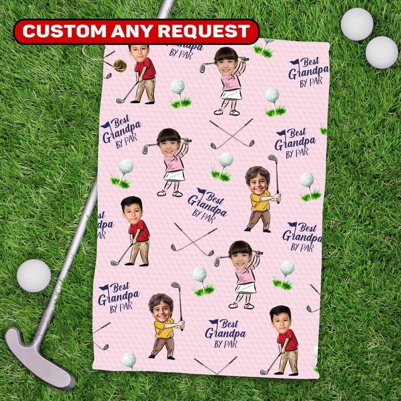 May include: Pink golf towel with a repeating pattern of cartoon golfers, golf balls, and crossed golf clubs. Text reads "Best Grandpa BY PAR" and "CUSTOM ANY REQUEST". The towel is on a green grass background.