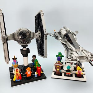 May include: Two LEGO Star Wars models: a gray TIE fighter and a white and gray spaceship. The TIE fighter is on a black base with several minifigures. The spaceship is on a white base with several minifigures.