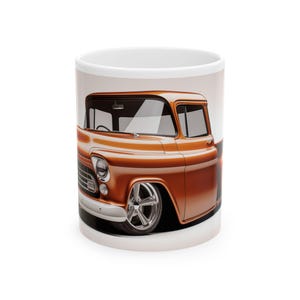 May include: A white ceramic mug featuring a detailed illustration of a classic orange pickup truck. The truck has chrome wheels and a shiny finish. The design wraps around the mug, showcasing the vehicle's front and side profile. The mug is a standard size.