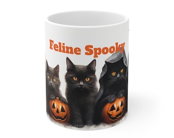 May include: White ceramic mug featuring three black cats with orange eyes and jack-o'-lanterns. The mug has the words "Feline Spooky" in orange. A Halloween-themed design.