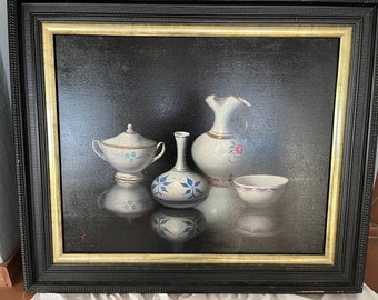 May include: A still life painting of four white ceramic pieces on a black background. The pieces include a pitcher, a vase, a sugar bowl, and a small bowl. The pieces are decorated with blue and gold floral patterns.