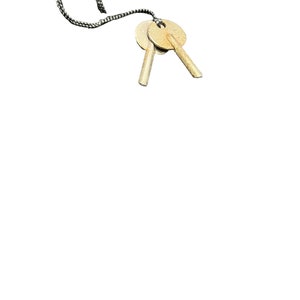 May include: Two gold-colored keys attached to a black and white string.