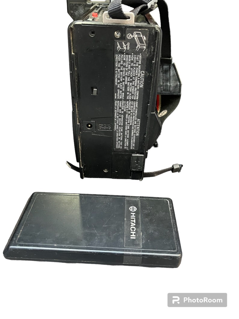 May include: A black Hitachi camcorder with a black strap and a black battery case. The camcorder has a power cord and a battery compartment. The battery case has the Hitachi logo on it.