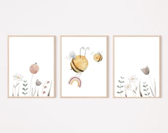 Op de afbeelding: Set van drie ingelijste aquarelprints. De prints tonen een bij met een regenboog, bloemen en een neutraal kleurenpalet. Het kunstwerk zit in een licht houten frame en is geschikt voor een kinderkamer.