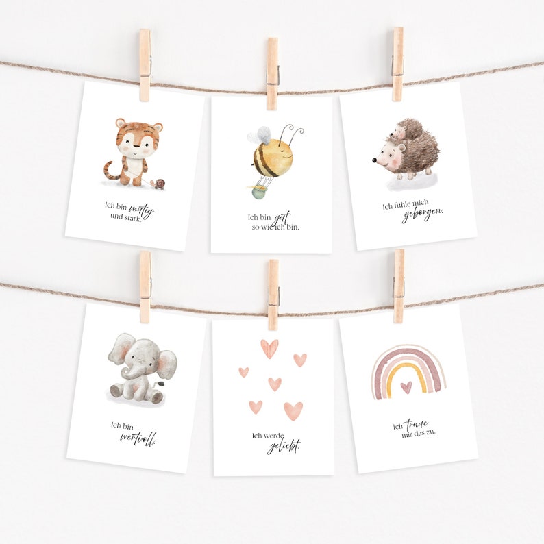 Puede incluir: Seis ilustraciones de acuarela en tarjetas blancas con una cuerda y pinzas para colgarlas. Las ilustraciones representan un tigre, una abeja, un erizo, un elefante, corazones y un arco&iacute;ris. Cada tarjeta tiene una frase en alem&aacute;n.