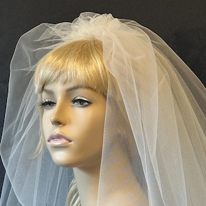 May include: A white single-tier bridal veil with a gathered tulle top and a soft, flowing design.