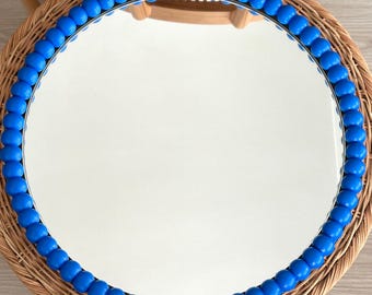 May include: A circular wall mirror featuring a frame composed of a single row of smooth, vibrant blue spherical beads. The reflective glass surface is clear and circular, framed by the continuous line of bright blue beads that create a textured border.