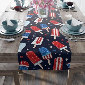 May include: A navy blue table runner with a repeating pattern of red, white, and blue popsicles and white stars.