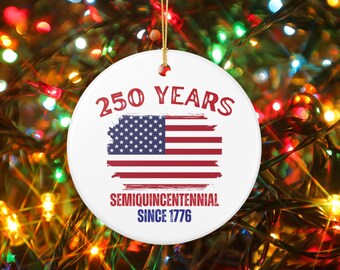May include: A round, white ceramic ornament with a patriotic theme. The ornament features the American flag and the text "250 YEARS" in red, along with "SEMIQUINCENTENNIAL SINCE 1776" in blue. A gold string is attached for hanging.