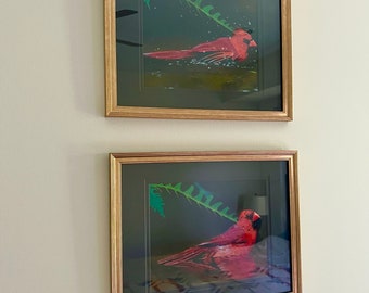 May include: Two framed pictures of red cardinals in a leafy setting. The top picture shows the cardinal swimming in a pool of water. The bottom picture shows the cardinal perched on a branch.