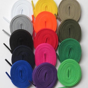 May include: A collection of fifteen round shoelaces arranged in a grid, featuring a variety of solid colors including white, yellow, tan, gray, orange, olive green, black, red, bright green, navy blue, hot pink, blue, purple, and lime green.