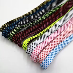 May include: Close-up of several colorful shoelaces. The laces are in various colors, including black, yellow, red, white, pink, and blue. Each lace has a diamond-shaped pattern. The laces are arranged diagonally across the image.
