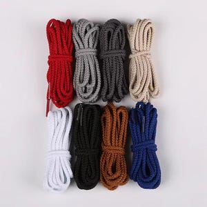 May include: An assortment of nine bundles of shoelaces in various colors. The colors include red, gray, dark gray, beige, white, black, brown, and blue. Each bundle is neatly tied and presented against a white background.